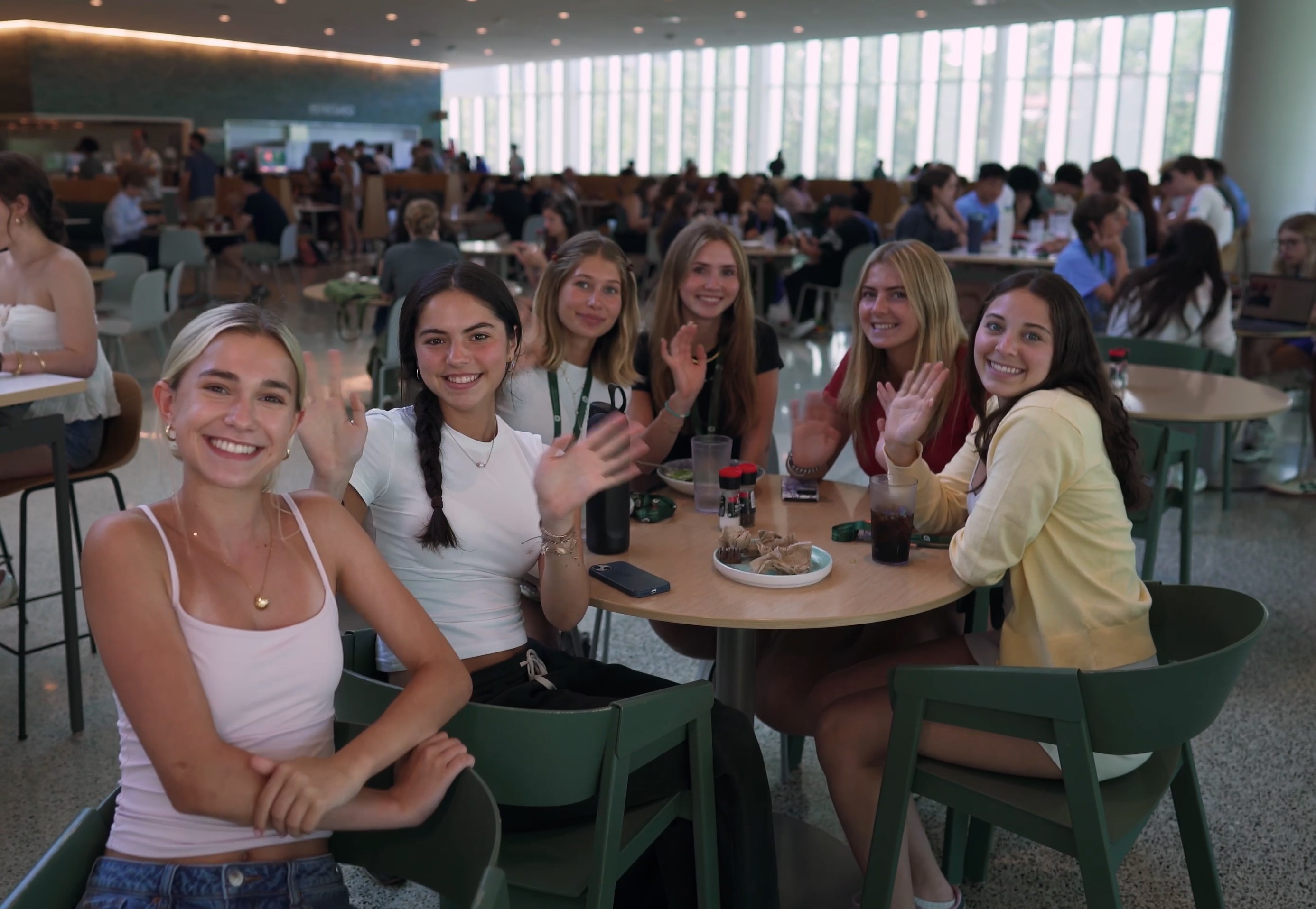 Group of pre-college students smiling and waving in the Commons