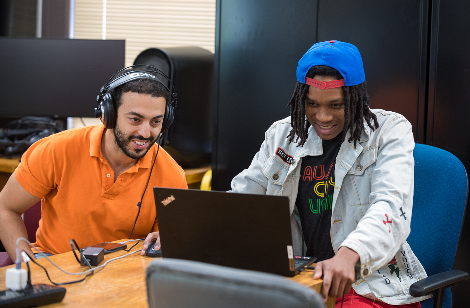 A professor assists a students working on computer coding projects.