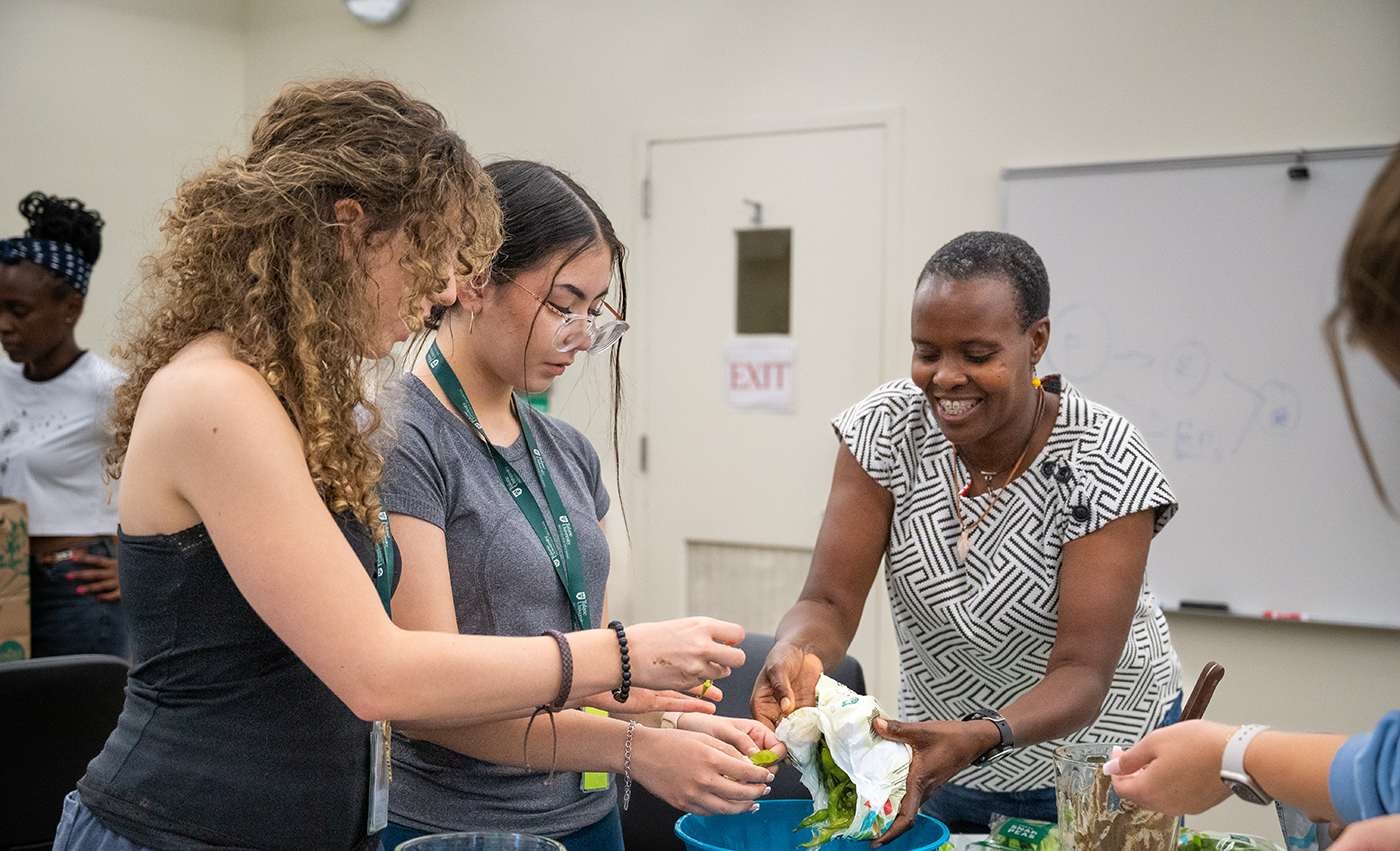 A professor assists two students with a lab in Intro to Plans and Human Affairs