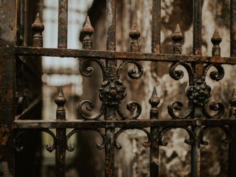 Close-up of an ornate cast iron gate outside of a cemetery in New Orleans.