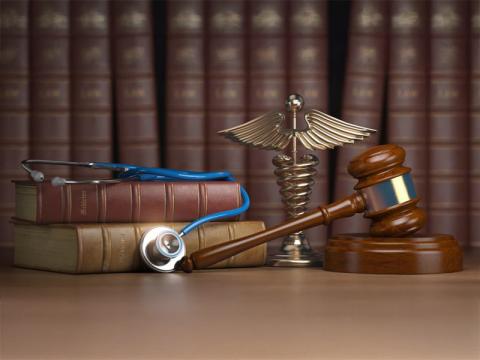 image of gavel, caduceus, and stethoscope on top of legal books.
