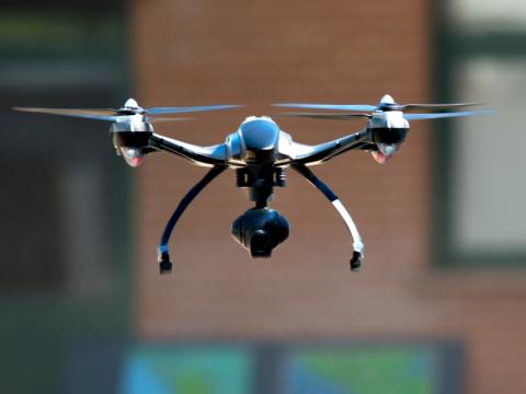 A drone with a camera attached hovers in the air.