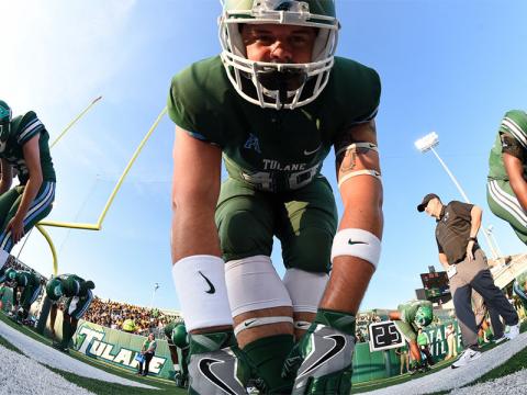 Football player in green uniform with white accents, focused and ready.