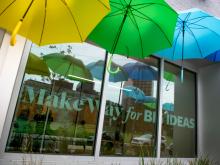 Colorful umbrellas hang over window of the Tulane Innovation Institute reflecting a "Make Way for Big Ideas."