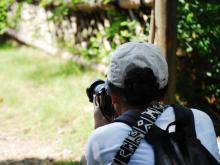 Person in a cap photographs with a camera.