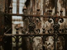Close-up of an ornate cast iron gate outside of a cemetery in New Orleans.
