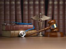 image of gavel, caduceus, and stethoscope on top of legal books.
