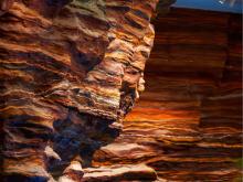 Canyon wall with vivid orange and brown layered rock formations.
