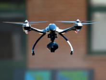 A drone with a camera attached hovers in the air.