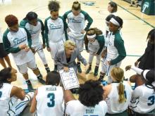 Coach shows Tulane Women's basketball team plays on a clipboard.